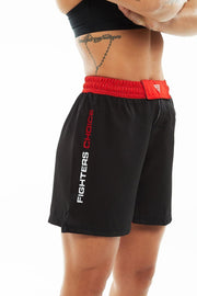 Right View of woman wearing black and red Fighters Choice Everlasting Fight Shorts, with the Fighters Choice name on the right leg pant, the apparel elite fighters use to Perform and look sharp on the BJJ mat