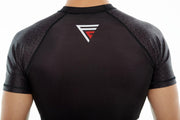 Man wearing black Fighters Choice Takeover Short Sleeve Rashguard, with the Fighters Choice logo prominently displayed in the back, the best apparel for Gi/NoGi fighters