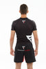 Man showing his back while wearing black Fighters Choice Takeover Short Sleeve Rashguard, with the Fighters Choice logo prominently displayed in the back, as well as an Everlasting Fighter Shorts, the best apparel for Gi/NoGi fighters